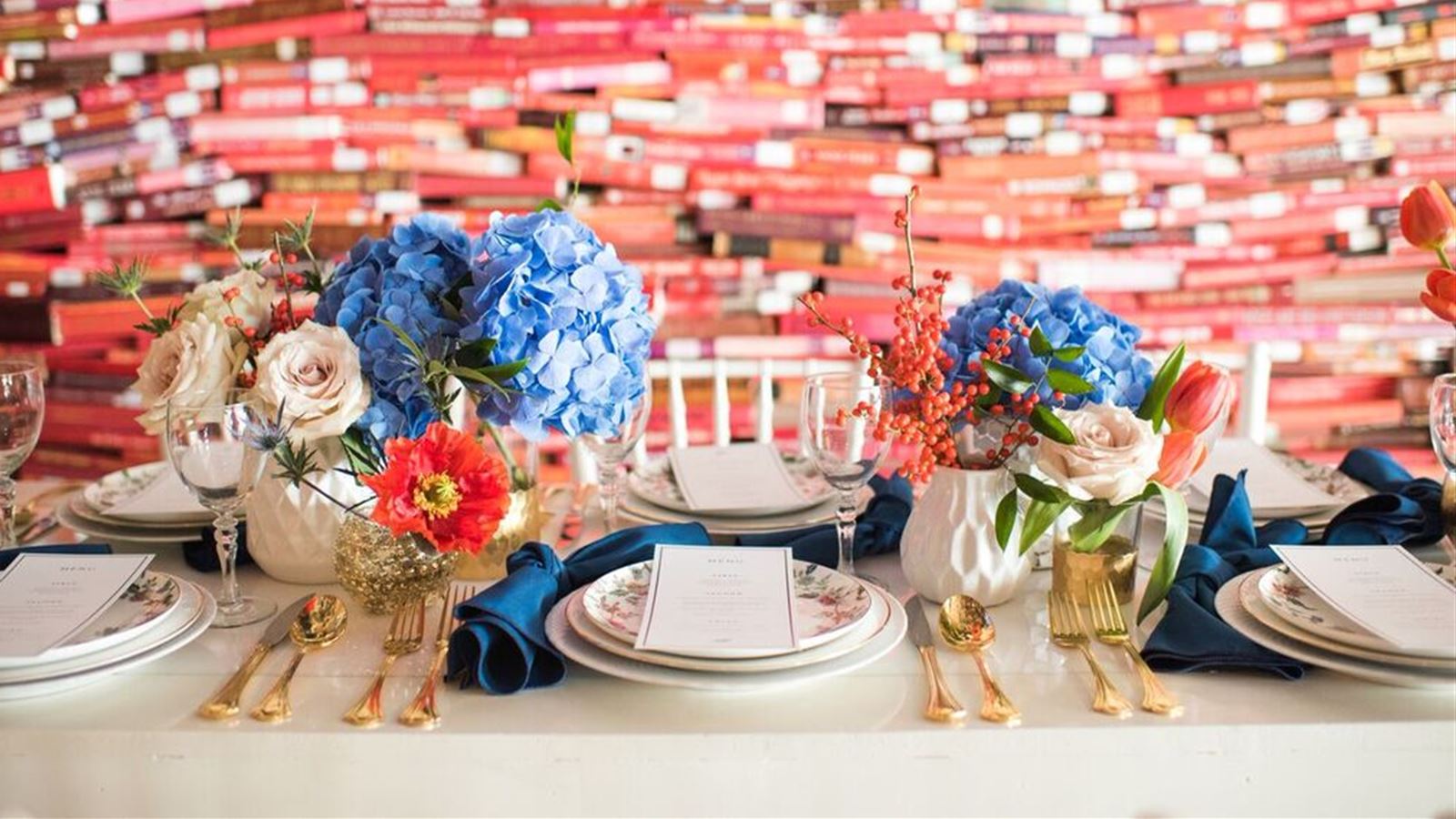 Wedding reception table set up in front of book wall